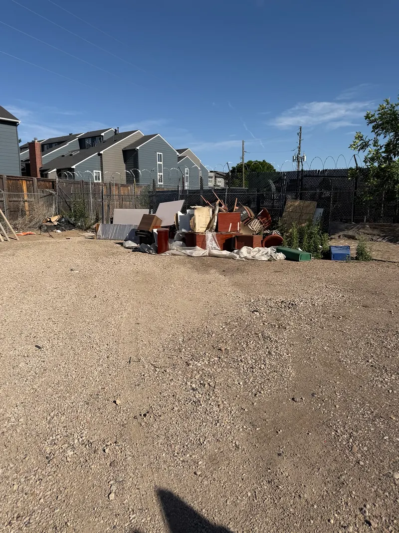 Before bulk furniture removal: unwanted furniture and bulky items piled beside a fence