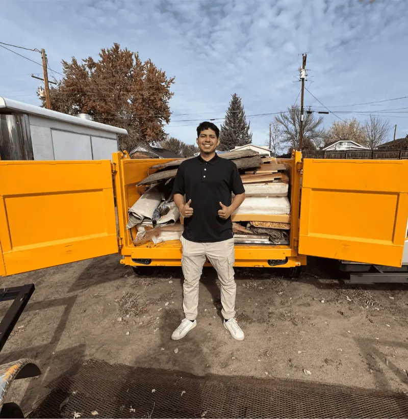 Emilio Preciado, co-owner of Buzz Off Junk, in front of a loaded yellow trailer