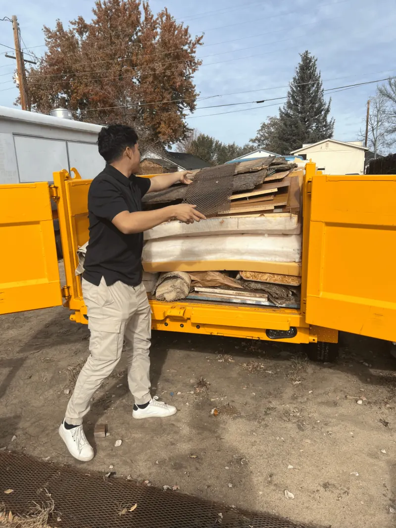 Buzz Off Junk crew member loading a yellow hauling trailer