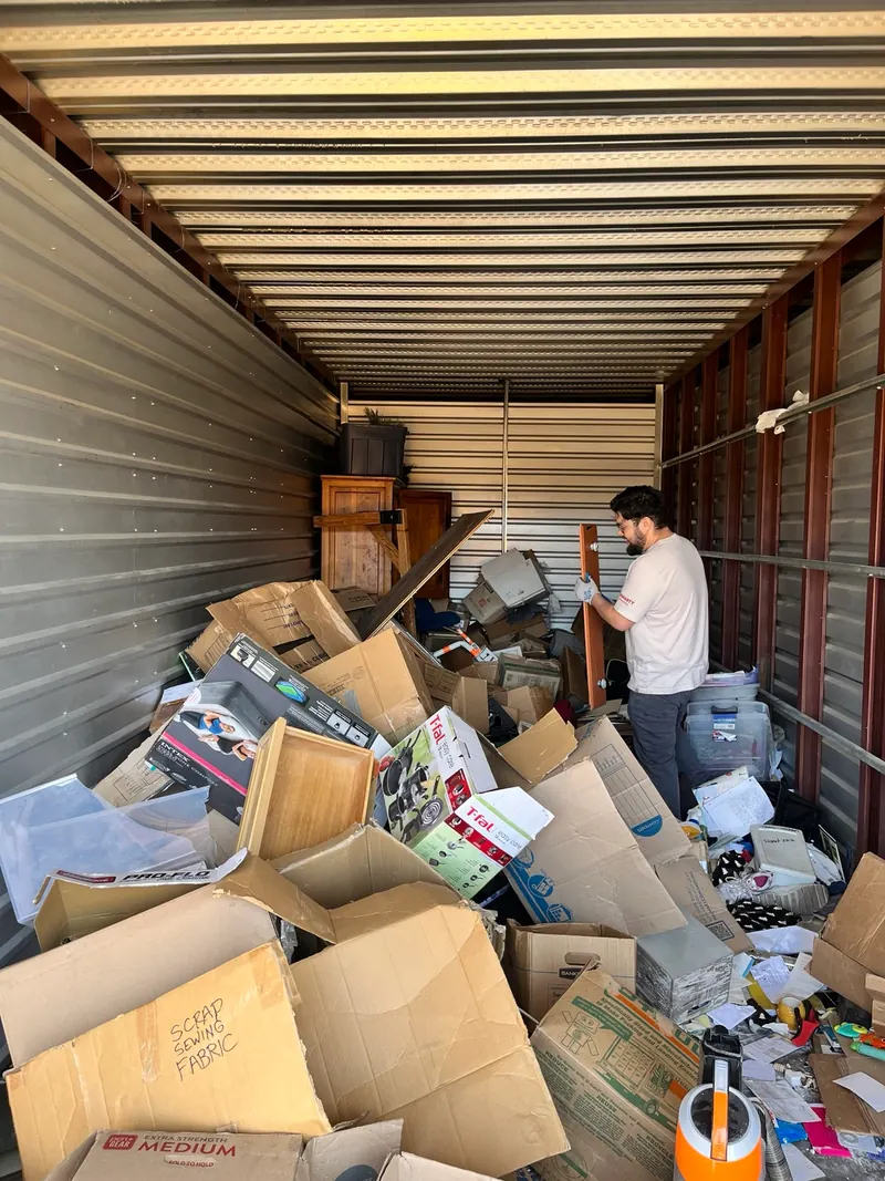 Before a storage unit cleanout: boxes, furniture and loose household items fill the unit